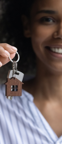 A woman smiling and holding up a house key.
